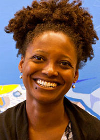 A smiling person with short, curly hair is facing the camera. They are wearing a dark jacket and small earrings. The background is blue with colorful abstract shapes, creating a bright, cheerful setting.