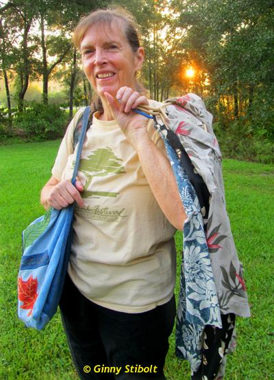 A photo of author Ginny Stibolt with tote bags outside.
