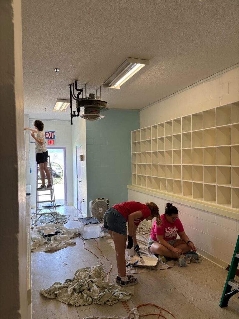 UPF staff painting shelves at the new library at Grace Marketplace.