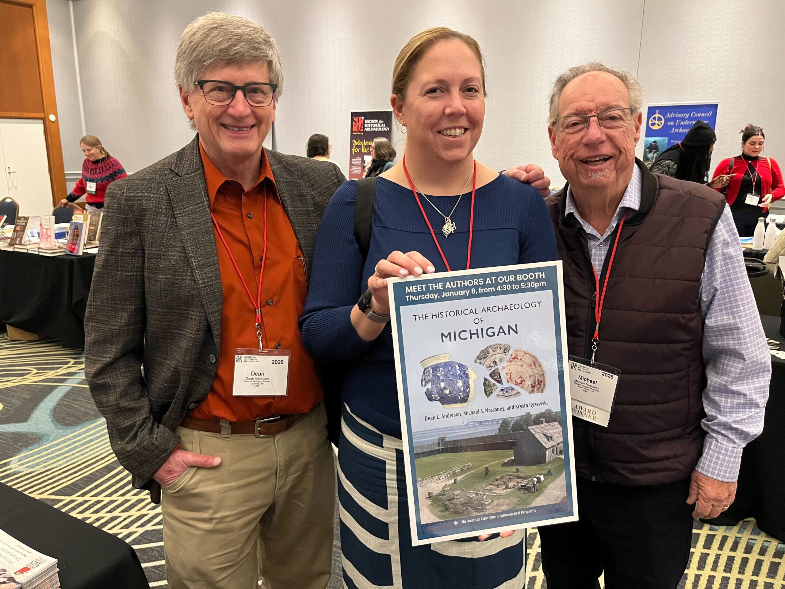 Dean Anderson, Krysta Ryzewski, and Michael S. Nassaney pose with a poster of their book cover.